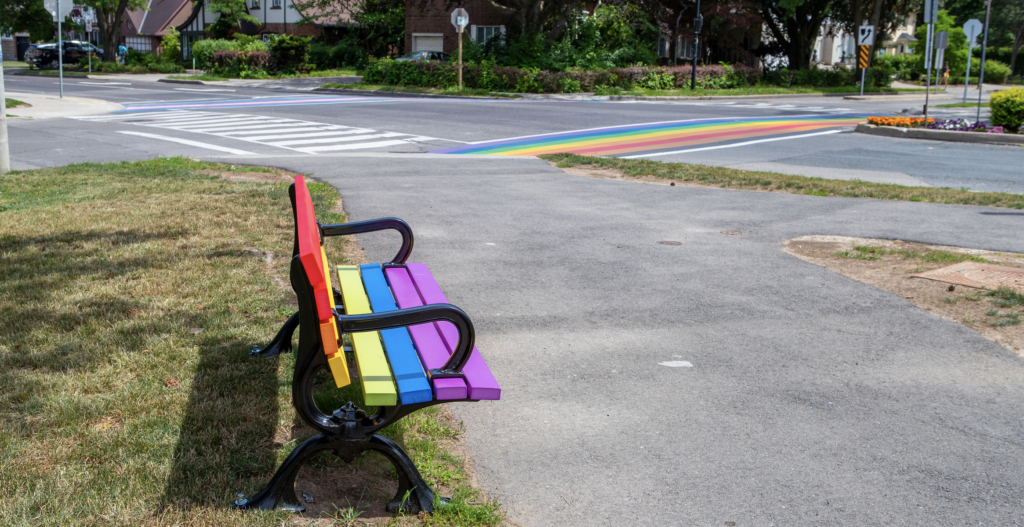 Park bench painted in rainbow flag colours.