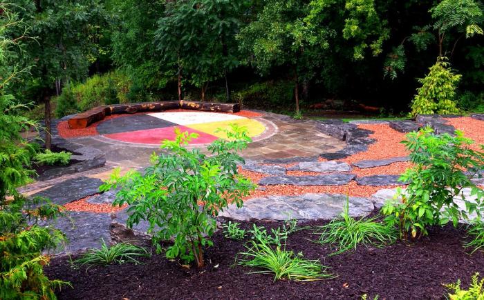 The Indigenous Circle is bordered by both the McMaster campus and the canopy of Cootes Paradise. The space features tired stone arranged around a stage in the form of a medicine wheel, a symbol that represents the interconnectivity of all beings. Plantings in the space were sourced from Six Nations of the Grand River. The area demonstrates the role nature and outdoor spaces play in teaching and learning and signifies the importance of Indigenous knowledge to the growth of the McMaster community.